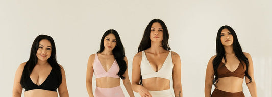 Four women walk forward in a bright white studio wearing matching coordinated activewear sets in black, light pink, off-white, and brown.